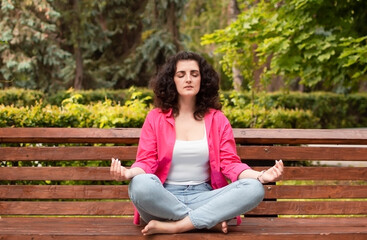 Obraz premium Girl does yoga in an outdoor summer park. Performs exercises to restore strength and spirit meditates, feeling Zen-style in a public park