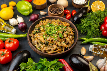 Close up view of delicious eggplant meal fresh vegetables spices fallen oil bottle green bundle on dark color background