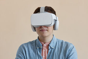 Portrait of young man in wireless VR glasses isolated on beige background