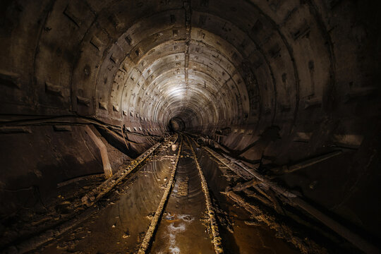 Dark dirty abandoned subway tunnel with rusty railway © Mulderphoto