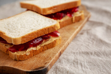 Homemade Peanut Butter and Jelly Sandwich on a rustic wooden board, side view.