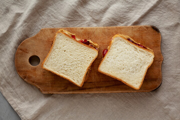 Homemade Peanut Butter and Jelly Sandwich on a rustic wooden board, top view.