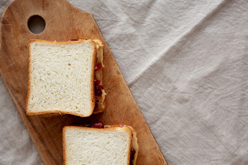 Homemade Peanut Butter and Jelly Sandwich on a rustic wooden board, top view.