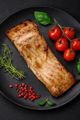 Slice of delicious baked fish with salt, spices and herbs on a ceramic plate