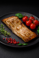 Slice of delicious baked fish with salt, spices and herbs on a ceramic plate