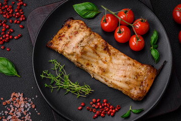 Slice of delicious baked fish with salt, spices and herbs on a ceramic plate