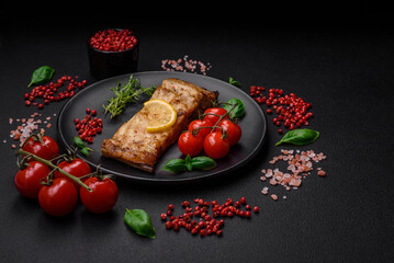 Slice of delicious baked fish with salt, spices and herbs on a ceramic plate