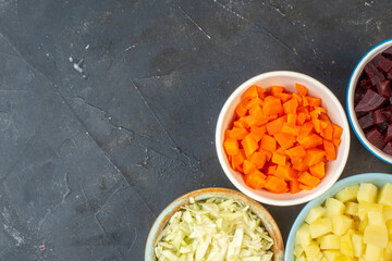 Half shot of set of chopped fresh foods in bowls on dark color background in above view