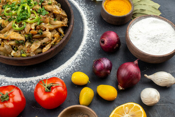 Horizontal view of eggplant dish served with green flour spices vegetables on black background