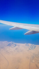 View from the window of plane on blue sky and earth with landscape of desert, sea and canals in Emirates. High quality photo