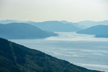 View over Ranfjorden going west from Hauknestinden, 800 m altitude. Peak of Hauknes, Mo i Rana. Mountains dramatically going down into the fjord water below. Clear skies during Norwegian summer. 