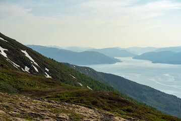 View over nordic mountain peaks in Norway from a hike up Hauknestinden, Hauknes, Mo i Rana, Helgeland, Norway. High peaks in a fjord landscape, snow covered. Clear Norwegian summer skies. Wild Norway - obrazy, fototapety, plakaty
