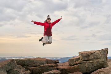 Carefree woman jumping on mountain cliff during sundown