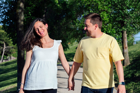 Happy couple in expectance walking in park