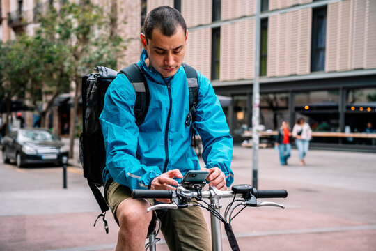 Man in service jacket using phone while riding bicycle