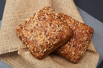 Two freshly baked rustic square shaped bread buns with sesame seeds extremely close up on the vintage rustic country style sackcloth