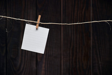 One alone white lined note sheet pinned on the rustic craft rope on the background of old wooden planks