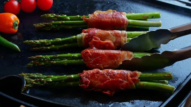 fried, cooking on grill green asparagus wrapped in jamon