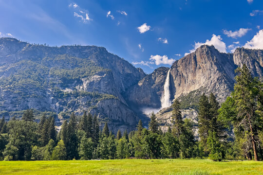 Yosemite meadow panorama with green grass and powerful waterfall