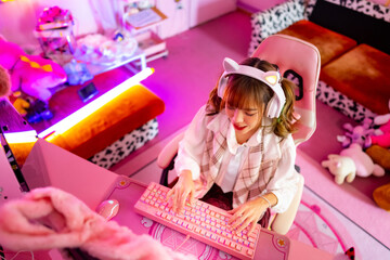 Young Asian woman esport player playing online game on computer in bedroom. Attractive girl vlogger influencer gamer enjoy and fun live streaming broadcast games challenge on social media platform. © CandyRetriever 