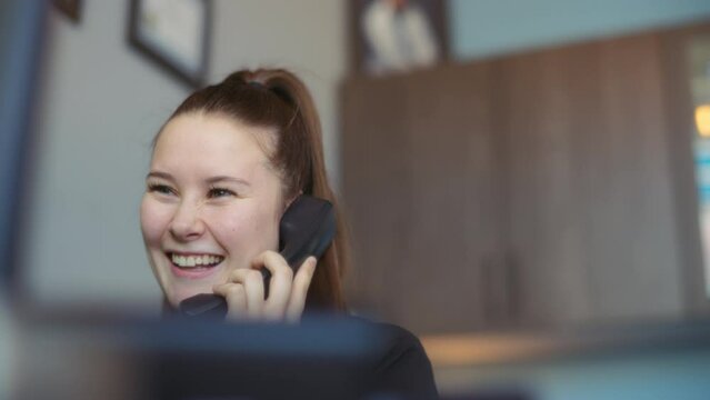 A receptionist smiling while talking with a customer on the phone. Slow motion. 
