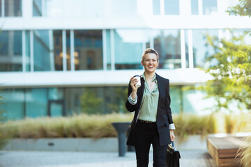 happy modern woman worker in business district walking