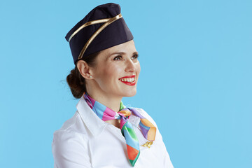 smiling modern female air hostess on blue looking into distance