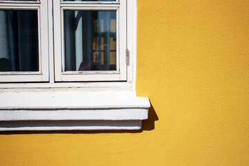 corner of a traditional white painted wooden window with a yellow painted wall