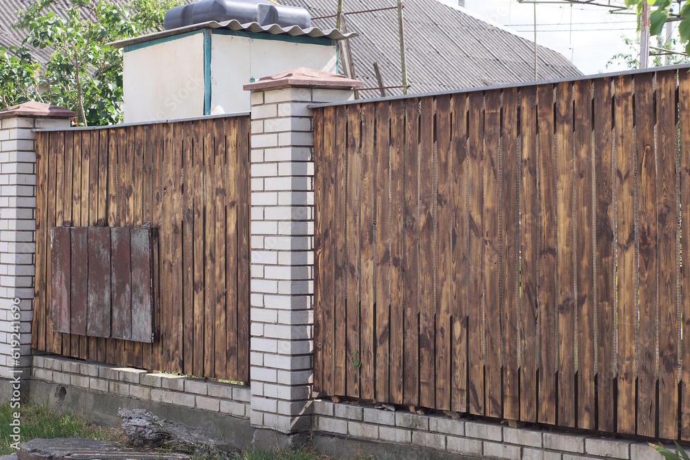 Sticker brown fence wall made of wooden boards and white bricks in the street 