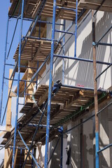 part of iron scaffolding structure with wooden boards near the white wall of the house on the street