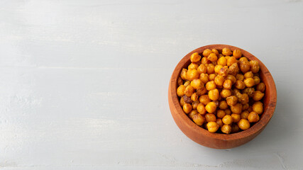 flatlay view of a wooden bowl filled with salty crispy chickpeas. over a white wooden table