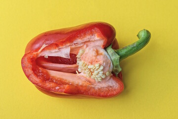 one piece of large ripe fresh red bell pepper lies on a yellow table