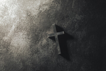 Chirstian cross or crucifix on dark stone floor.