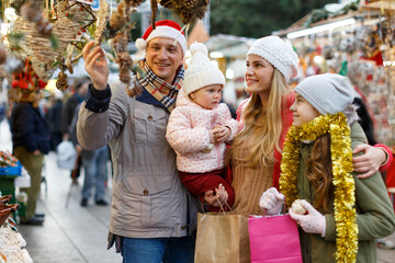 Portrait of cheerful man and woman with their happy daughters near counter buying Christmas decorations