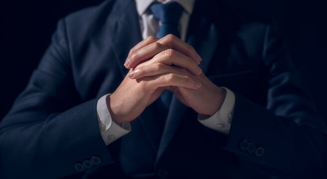 concept of business learning planing and pray. A business man is sitting in a meeting with hands crossed on the table.  praying, hope and negotiation in business dealing