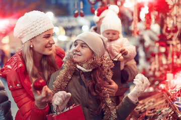 Happy mother and daughter choosing Christmas decoration at Christmas fair