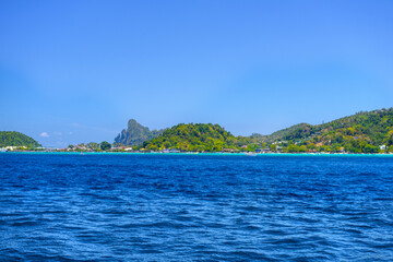 Fototapeta premium Motor ship in the bay of Ko Phi Phi Don Island with huge rocks and cliffs on a sunny day, Ao Nang, Mueang Krabi District, Krabi, Andaman Sea, Thailand