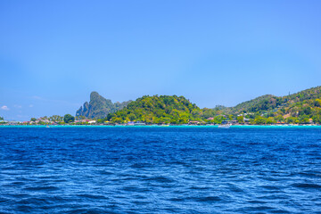 Naklejka premium Motor ship in the bay of Ko Phi Phi Don Island with huge rocks and cliffs on a sunny day, Ao Nang, Mueang Krabi District, Krabi, Andaman Sea, Thailand