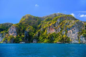 Fototapeta na wymiar Motor ship in the bay of Ko Phi Phi Don Island with huge rocks and cliffs on a sunny day, Ao Nang, Mueang Krabi District, Krabi, Andaman Sea, Thailand