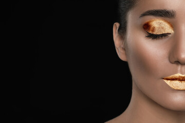 Fototapeta premium Young woman with beautiful gold makeup on black background, closeup. Space for text