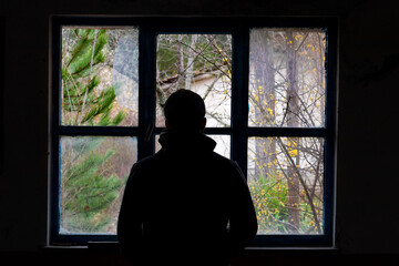 Silhouette of a man shot from behind in front of a shattered window