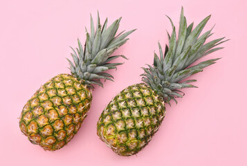 Fototapeta premium Delicious ripe pineapples on pink background, flat lay