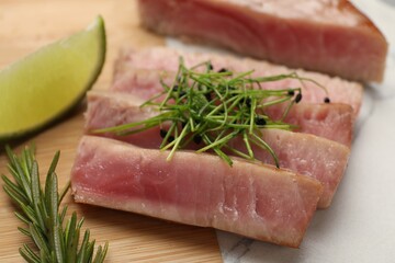 Pieces of delicious tuna steak with microgreens and rosemary on board, closeup