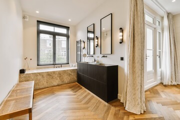 Fototapeta na wymiar a modern bathroom with wood flooring and black cabinetd bathtub in the center of the room is a wooden bench