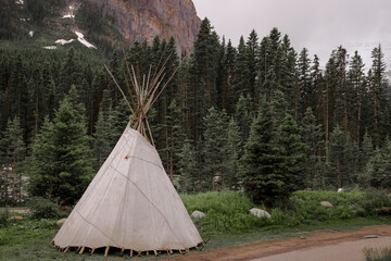 A wigwam tent is standing in the forest. Active recreation in the mountains. Hiking, camping, shelter in the Rocky Mountains, Alberta, Canada © joi