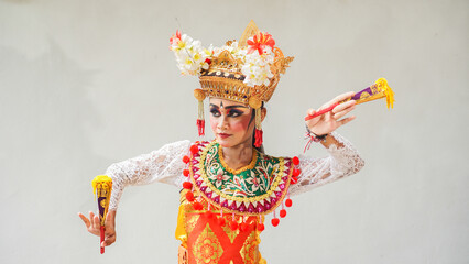 girl wearing Balinese traditional dress with a dancing gesture on white background with hand-held...