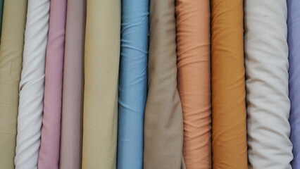 various types of rolled colorful fabrics with plain colors neatly arranged for the background
