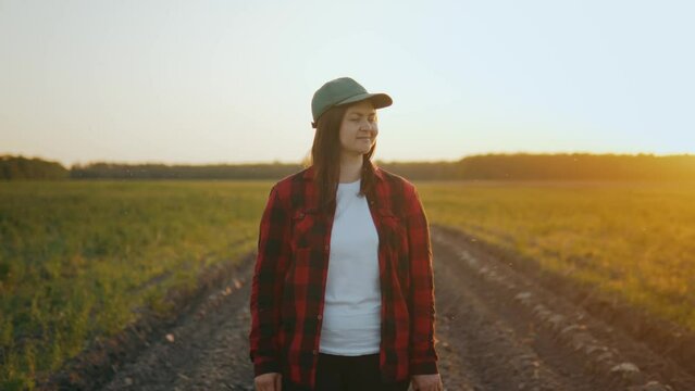 Portrait of an agronomist girl in a cap in the field looking at the camera