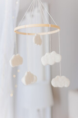 Baby mobile with white felt clouds hanging from a simple wooden circle