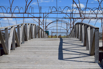 Wooden pedestrian bridge made of planks on the background of an unfinished canopy